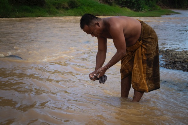 Samin Ahmad, warga Desa Bukit Tinggi yang mencuci baju meskipun kondisi air sungai tampak sangat keruh. (Foto: Sarjan Lahay)